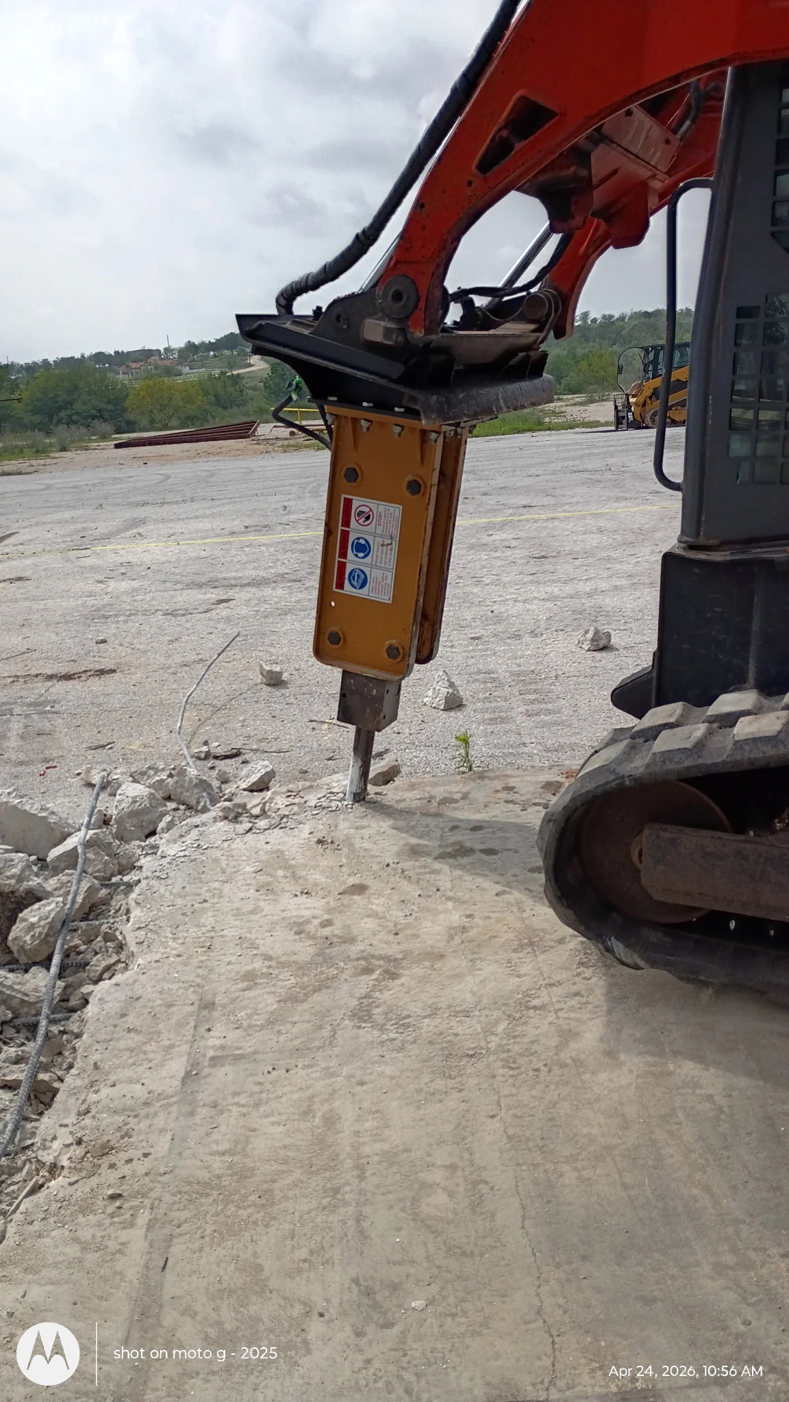 Hydraulic breaker attachment on excavator breaking large rocks at construction site